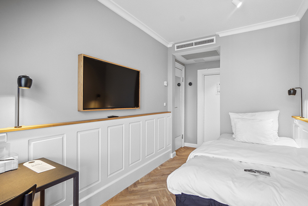 Et standard enkeltværelse på Hotel Kong Arthur med seng, fjernesyn og skrivebord.