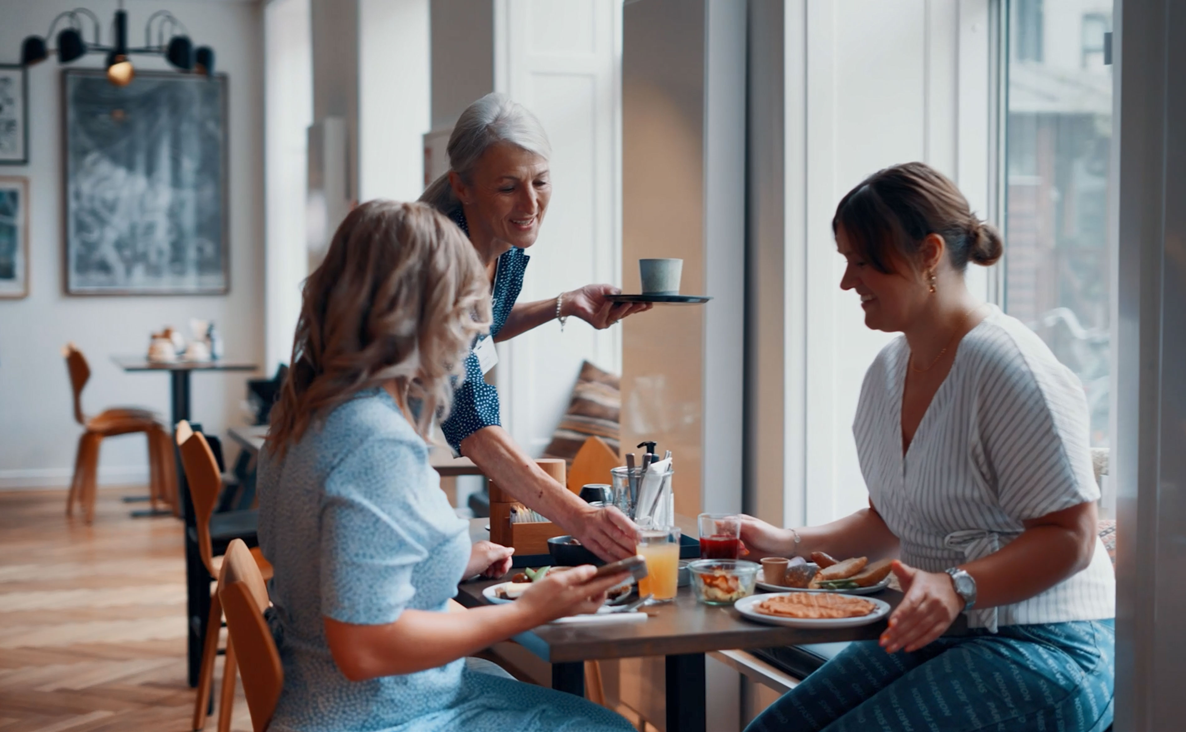To kvindelige gæster får serveret kaffe til deres morgenmad.